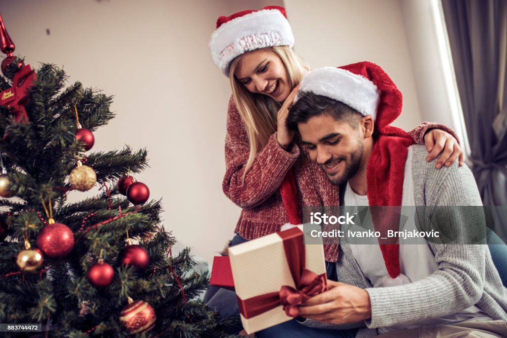 冬の日にクリスマスツリーの間で降る雪の下でキスをするカップル 写真背景 無料ダウンロードのための画像 - Pngtree