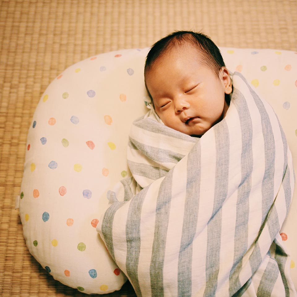 おひな巻き」 タオルやおくるみなどで、赤ちゃんの身体を丸く包む、写真のような方法を おひな巻きと言います。おなかの中にいた時のようなまるまった姿勢は、赤ちゃんが安心します。 また、突然「ビクッ」と両手足を広げる原始反射であるモロー反射を防ぎ、 赤ちゃんが