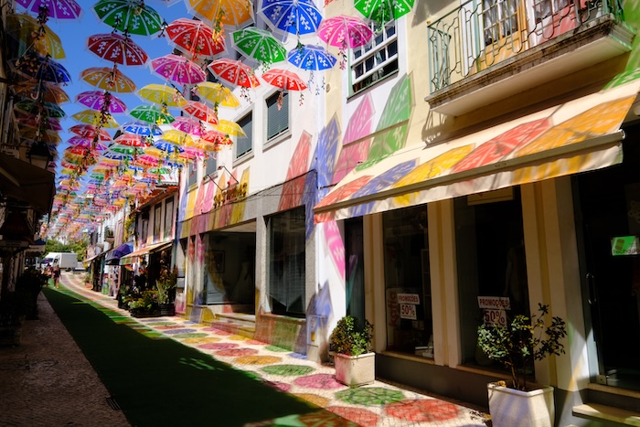 アゲダの傘祭り☂️ 今や世界中の観光地で見るこの色とりどりの傘が吊るされてる光景は、ポルトガルの小さなアゲダという町からはじまった🇵🇹発端は「日差しが強すぎるから傘でも吊るしてみるか！日除にもなるし目でも楽しめるしいいね！」くらいの感じだったらしい